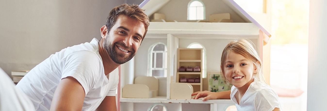 Man en kind zitten voor poppenhuis